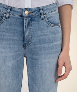 Close-up of light blue jeans with a beige background