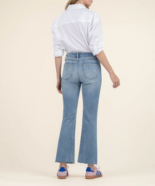 Person wearing light blue jeans and a white shirt on a beige background
