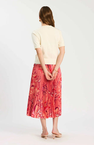 Woman wearing a light-colored top and red floral skirt on a white background