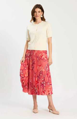 Woman wearing a cream blouse and red floral skirt on a white background